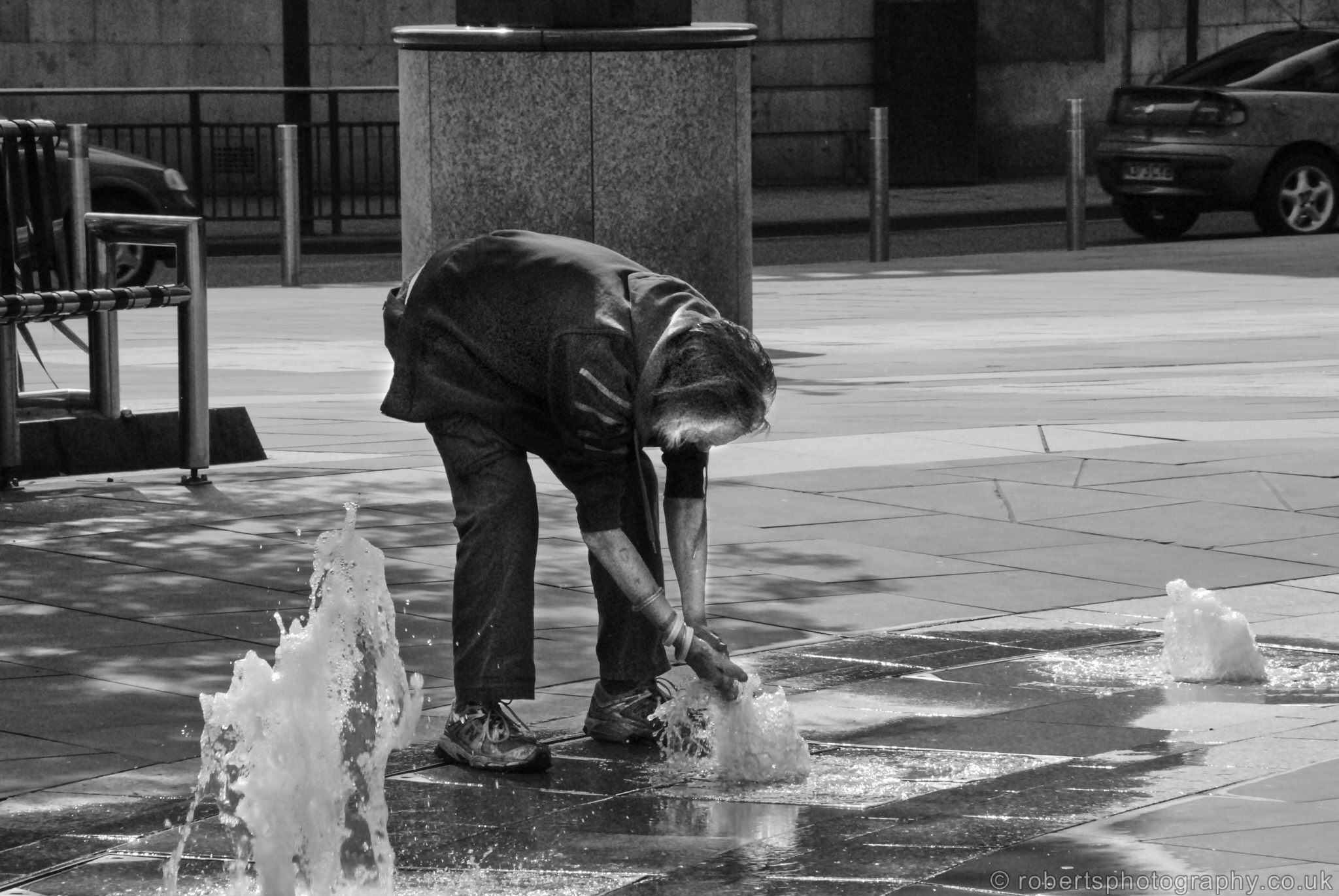 Homeless man is pictured taking a wash in a fountain, City Square, Leeds, West Yorkshire