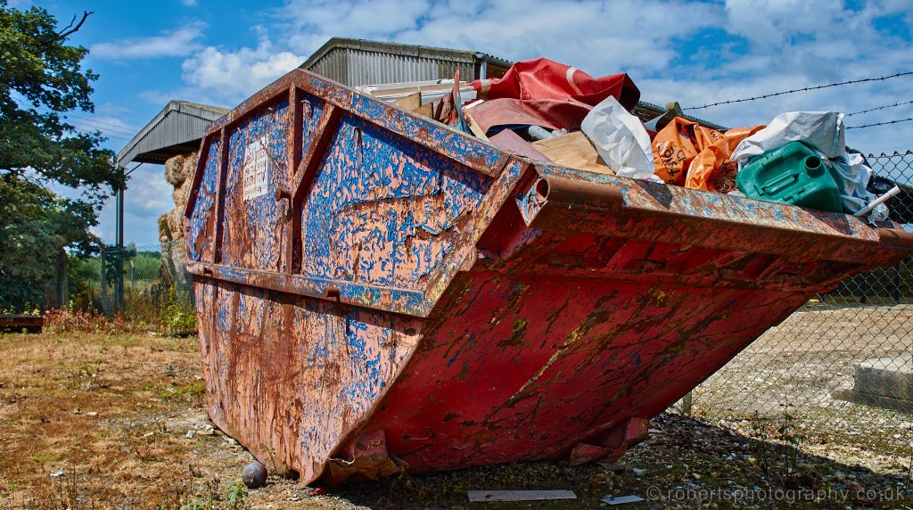 A colourful skip full of junk, awaits collection.
