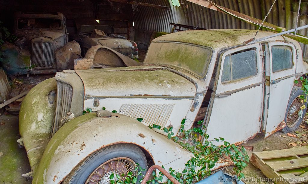 This vintage Jag in a shed, and others in the background too.