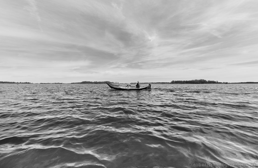 Two women are pictured in a small motorboat, navigating across the Bovenwijde Lake of Giethoorn, Overijssel in the Netherlands.
