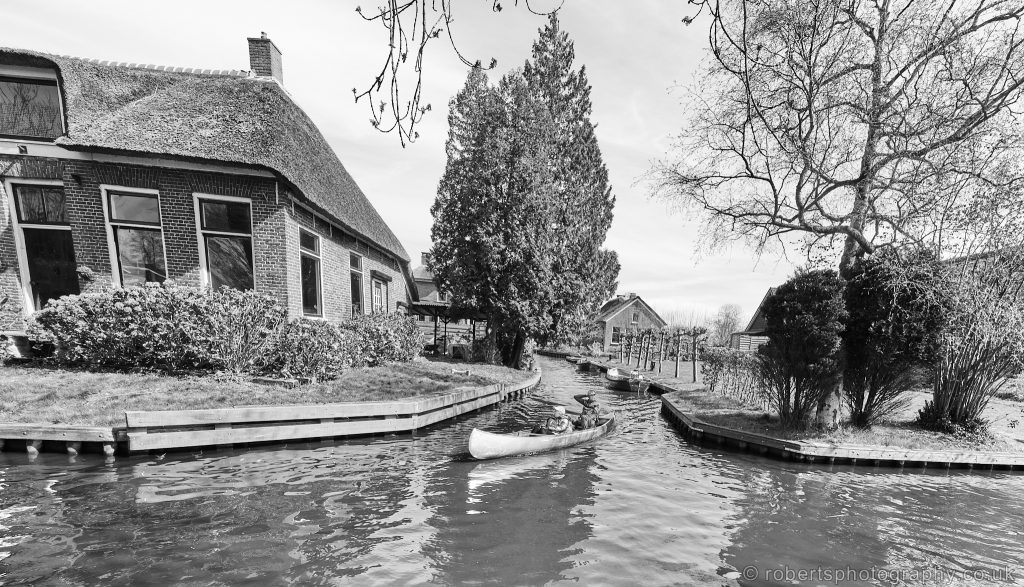 Two people pictured navigating the narrow canals of Giethoorn, Overijssel in the Netherlands.